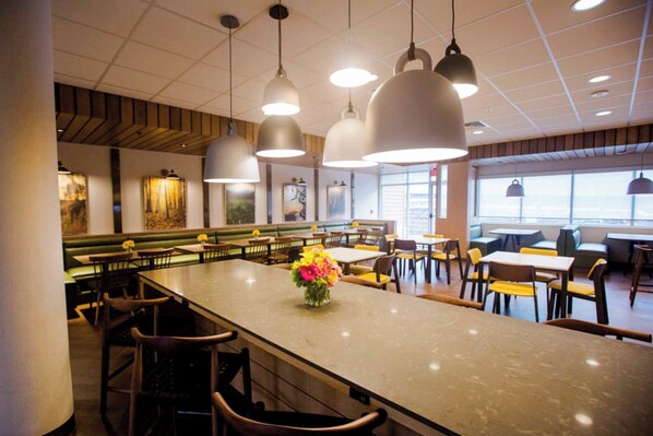 A restaurant interior with a long counter, multiple seating areas, pendant lighting, and artwork on the walls. - Fairfield Inn & Suites Philadelphia Broomall/Newtown Square (Broomall)