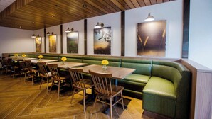 A restaurant with wooden flooring, green cushioned booths, and wooden tables with yellow flowers. - Fairfield Inn & Suites Philadelphia Broomall/Newtown Square (Broomall)