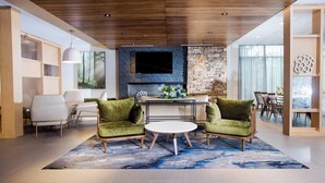 A modern living room with a stone fireplace, a flat-screen TV, and a dining area with a table and chairs. - Fairfield Inn & Suites Philadelphia Broomall/Newtown Square (Broomall)