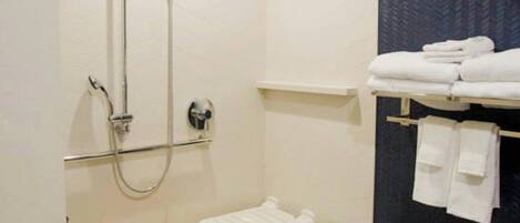 A modern bathroom with a walk-in shower, a toilet, and a towel rack with folded towels.