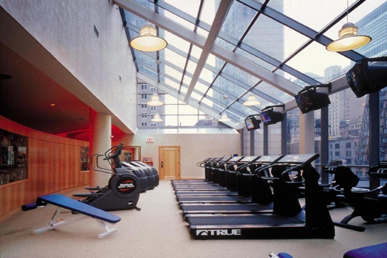 Un gimnasio con cintas de correr, una banca y bicicletas estáticas.