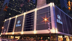 A hotel with a prominent Hilton sign, large windows, and a modern architectural design. - The Residences by Hilton Club (New York)