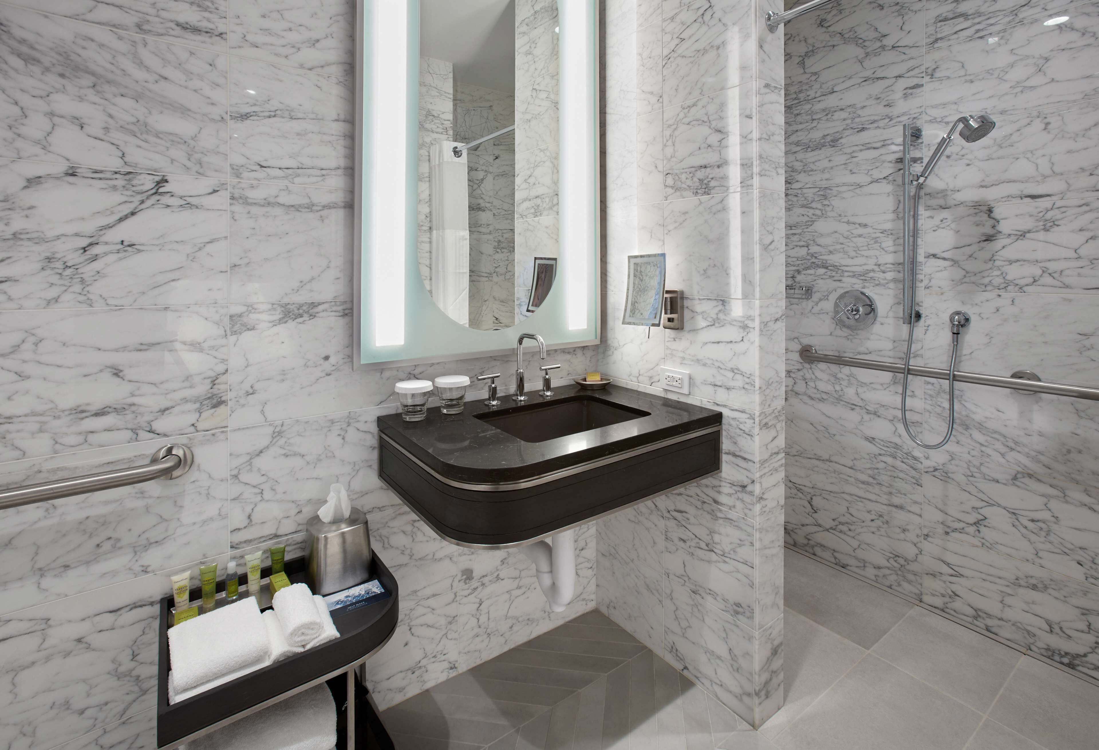 A modern bathroom with a marble sink, a large mirror, and a shower area.