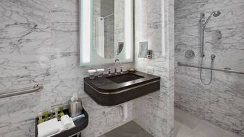 A modern bathroom with a marble sink, a large mirror, and a shower area.