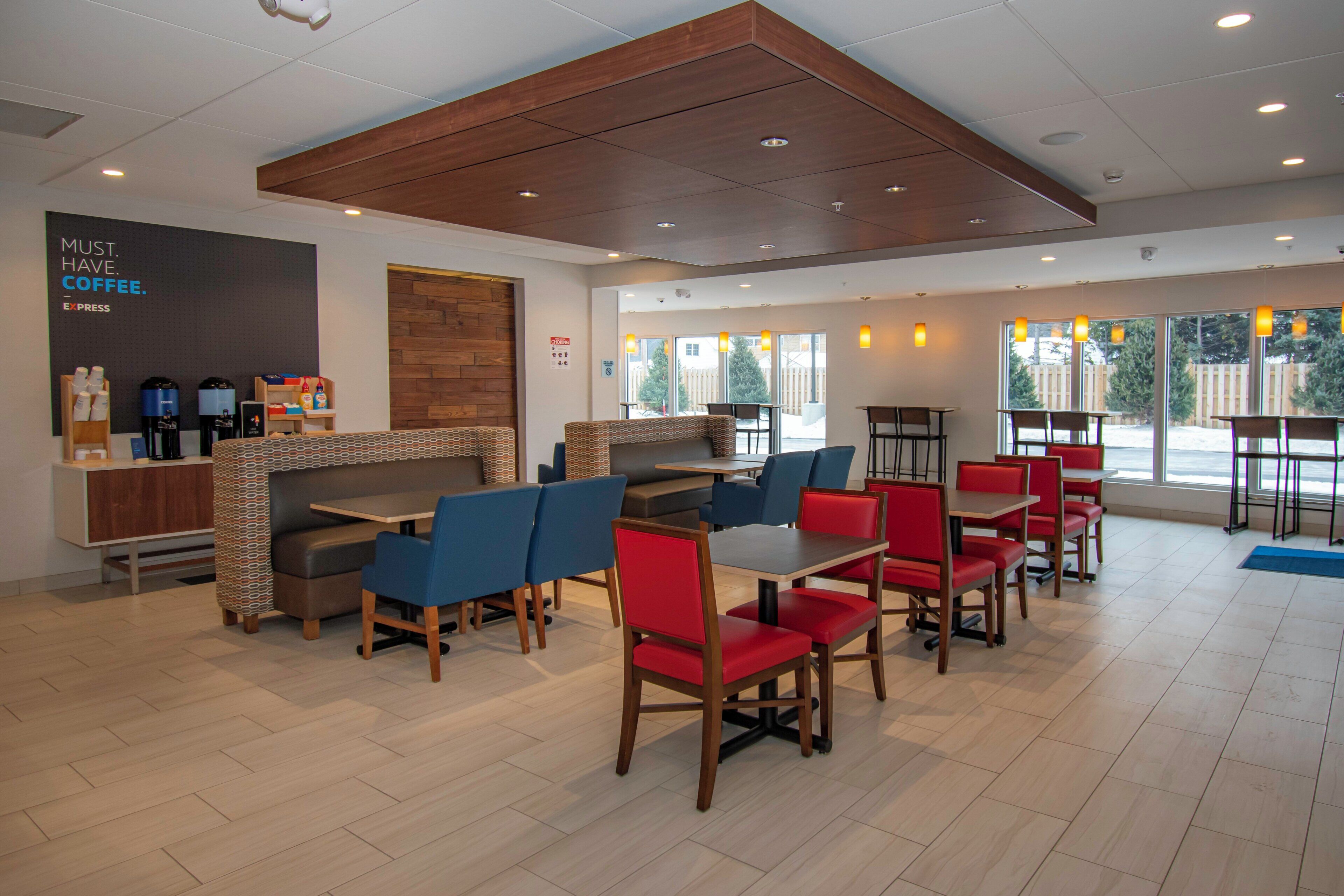 A modern cafe with seating arrangements, a coffee station, and large windows providing natural light.