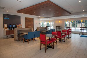 A modern cafe with seating arrangements, a coffee station, and large windows providing natural light. - Holiday Inn Express & Suites Tonawanda - Buffalo Area by IHG (Tonawanda)