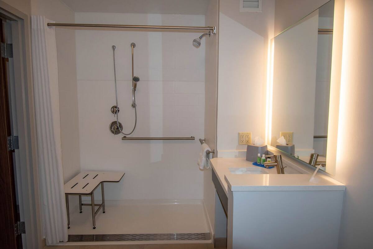 Un bagno moderno con doccia a filo pavimento, un water e un lavandino.