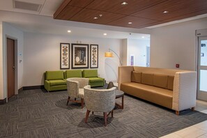 A hotel lobby with a green sofa, a patterned sofa, and two armchairs. There are framed artworks on the wall and a floor lamp. - Holiday Inn Express & Suites Tonawanda - Buffalo Area by IHG (Tonawanda)