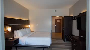 A hotel room with a bed, bedside table, TV, wardrobe, and a door leading to another room.