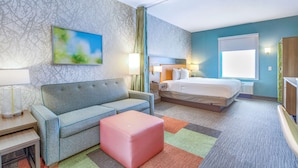 Een hotelkamer met een bed, een bank, een klein tafeltje en een kleurrijk vloerkleed.