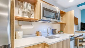 Een moderne keuken met roestvrijstalen apparatuur, houten kastjes en een wit aanrecht.