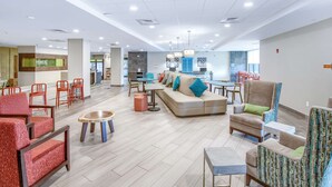 Een ruime lobby met een centraal zitgedeelte, een kitchenette en een receptiebalie.