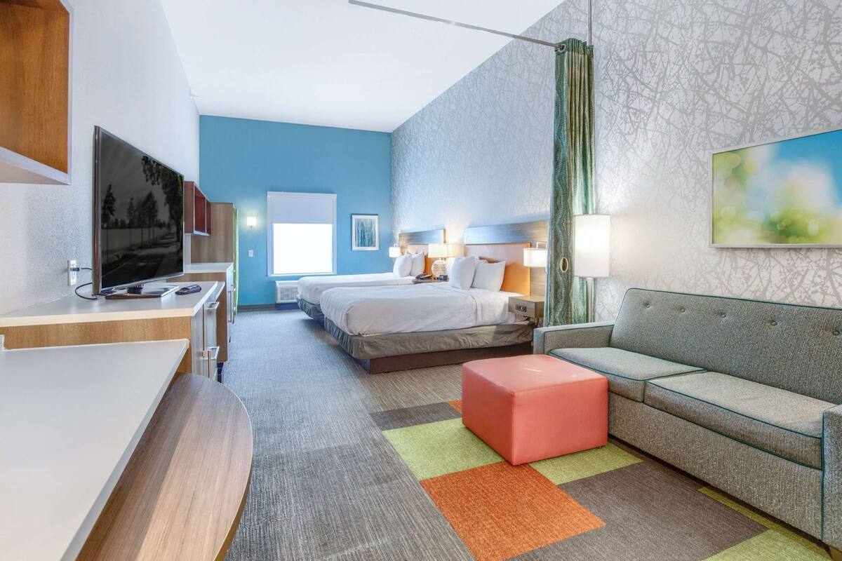 A hotel room with a bed, a sofa, a TV, and a desk.