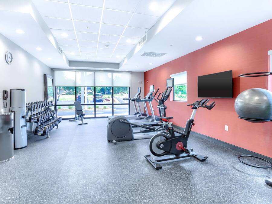 A gym with cardio machines, dumbbells, and a large exercise ball.