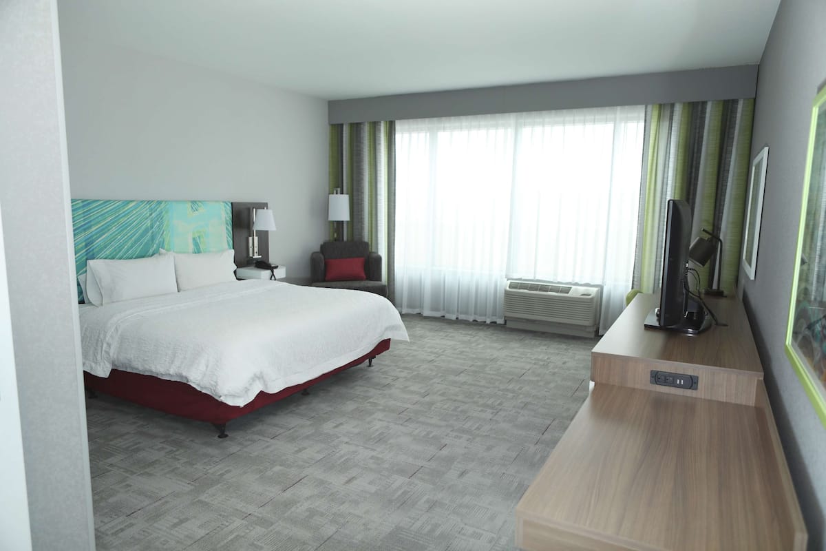 Une chambre d’hôtel équipée d’un lit, d’un bureau, d’une chaise, d’une télévision et d’une fenêtre avec des rideaux.