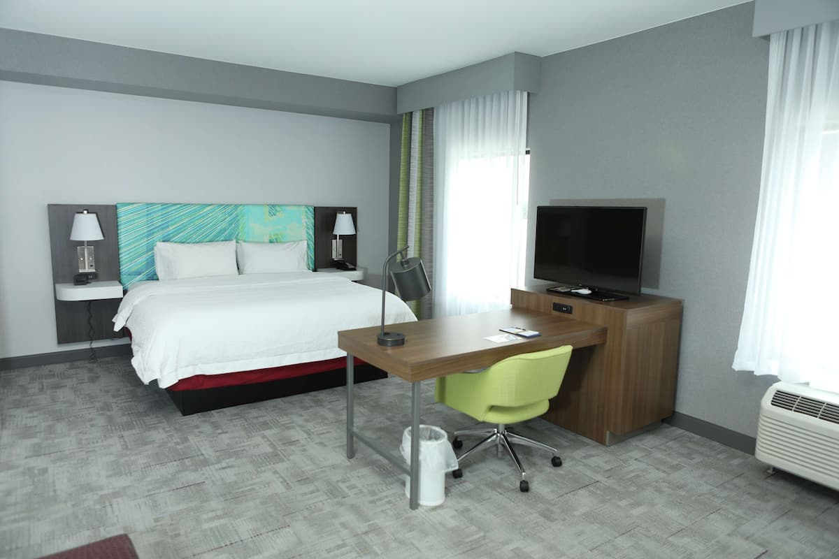 Une chambre d’hôtel équipée d’un lit, d’un bureau, d’une chaise, d’une télévision et d’une poubelle.