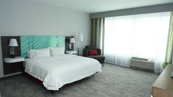 A hotel room with a large bed, a chair, a desk, and a window with curtains.