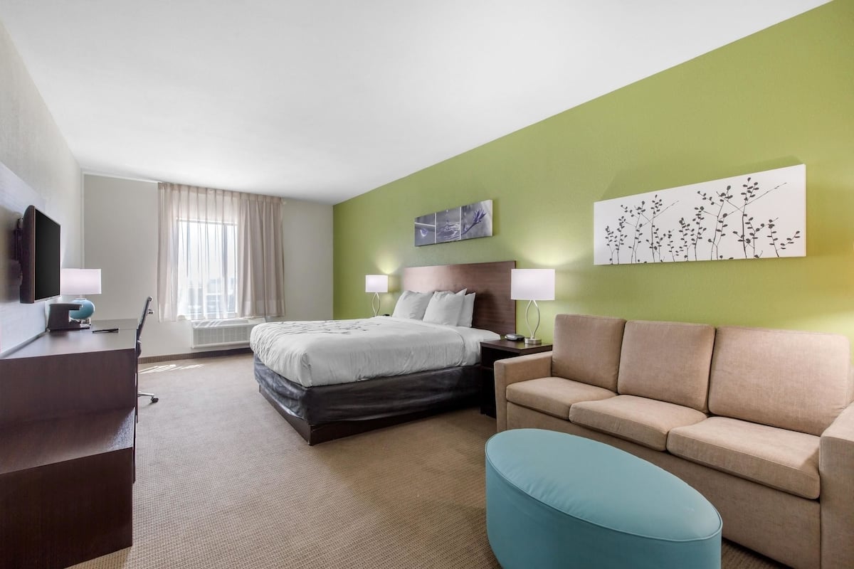 Ein Hotelzimmer mit Bett, Sofa, Schreibtisch und Fernseher.