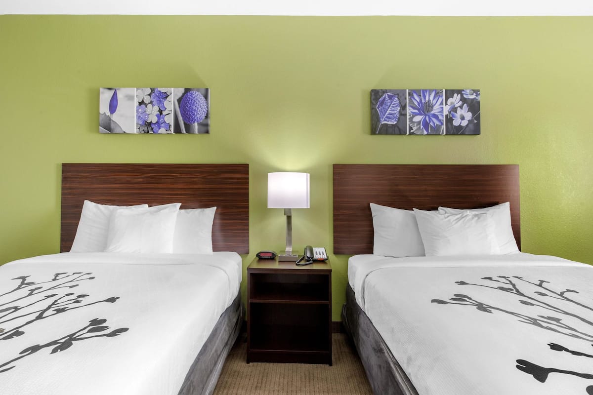 Ein Hotelzimmer mit zwei Betten, einem Nachttisch mit Lampe und Bildern an den Wänden.