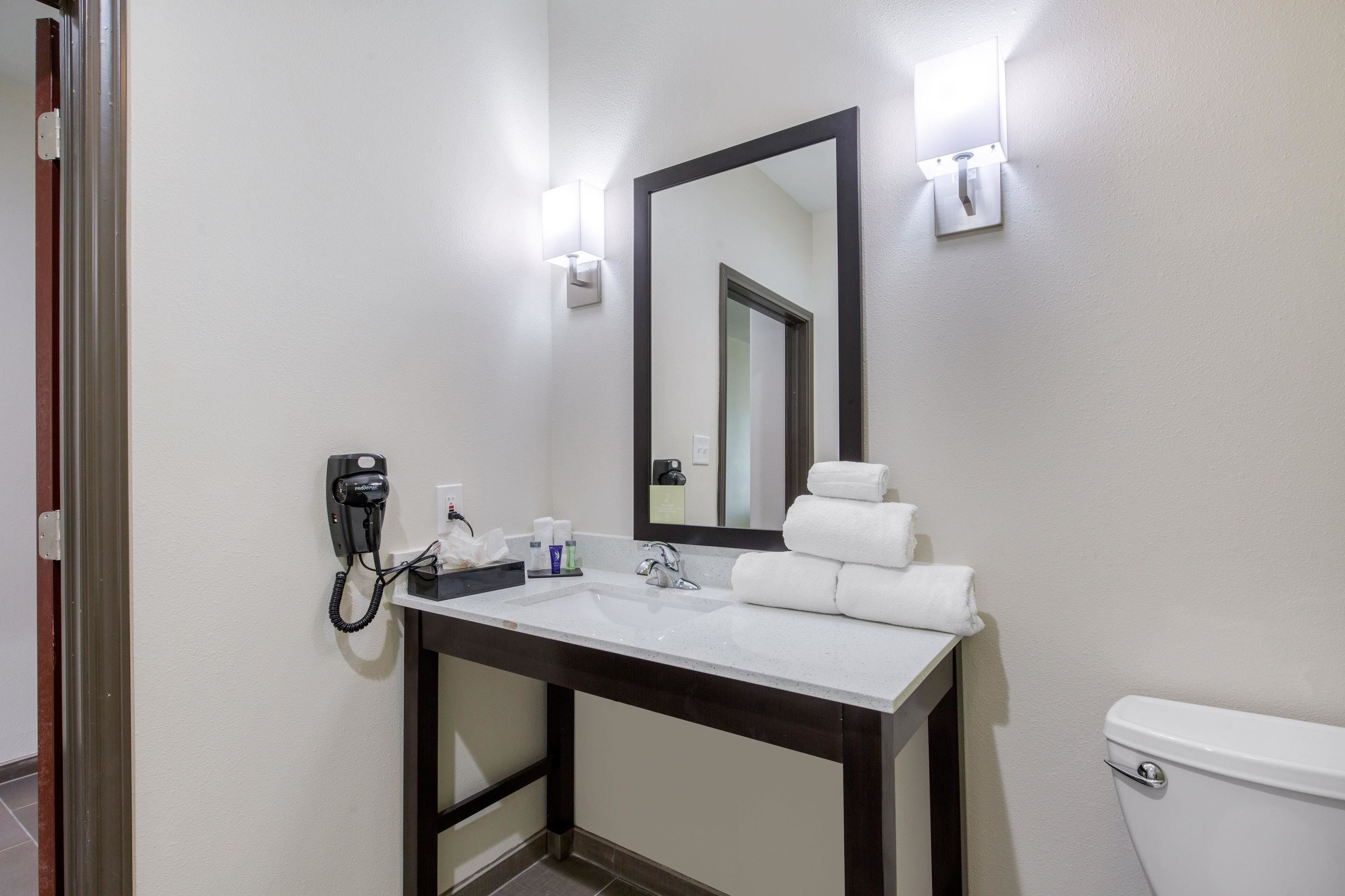 A bathroom with a white sink, a mirror, a toilet, and a telephone.
