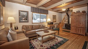A cozy living room with a sofa, coffee table, and a fireplace. - Willow by Hauserman Rentals (Tahoe City)