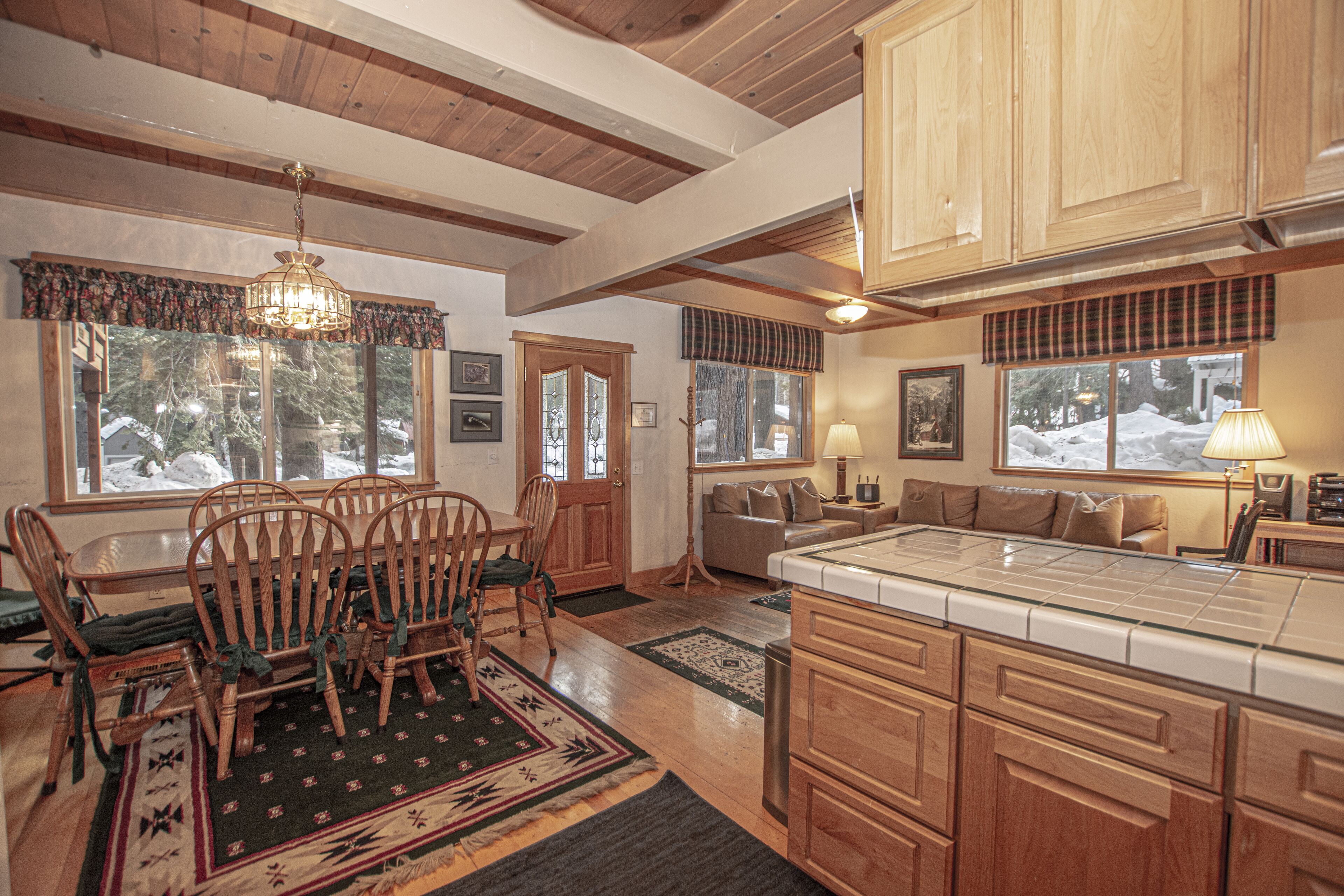 A spacious kitchen with wooden cabinets, a dining area with a table and chairs, and a cozy living room with a sofa and a fireplace.