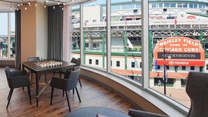 A spacious room with a large window overlooking Wrigley Field, a view of the Chicago Cubs stadium, and a chessboard on the table. - Hotel Zachary Chicago, a Tribute Portfolio Hotel (Chicago)