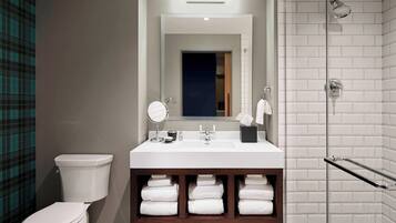A modern bathroom with a white sink, mirror, and towel rack.