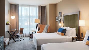 A hotel room with two beds, a desk, a chair, and a large window with curtains.