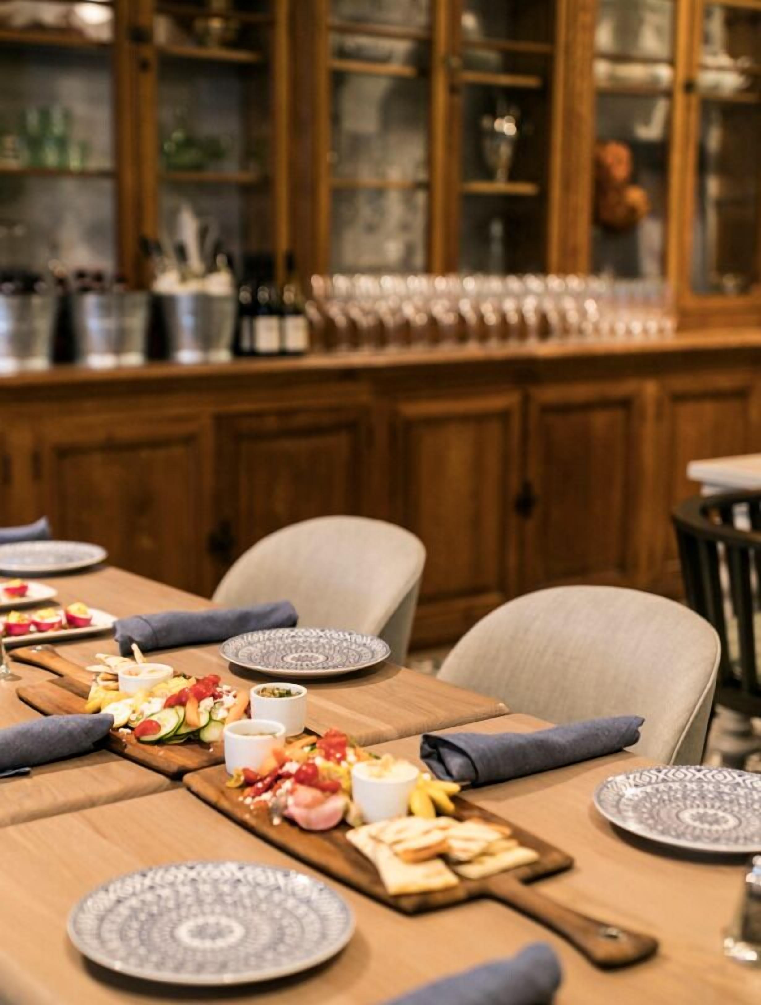 A dining area with a wooden table set for a meal, featuring plates, cutlery, and a variety of food items.