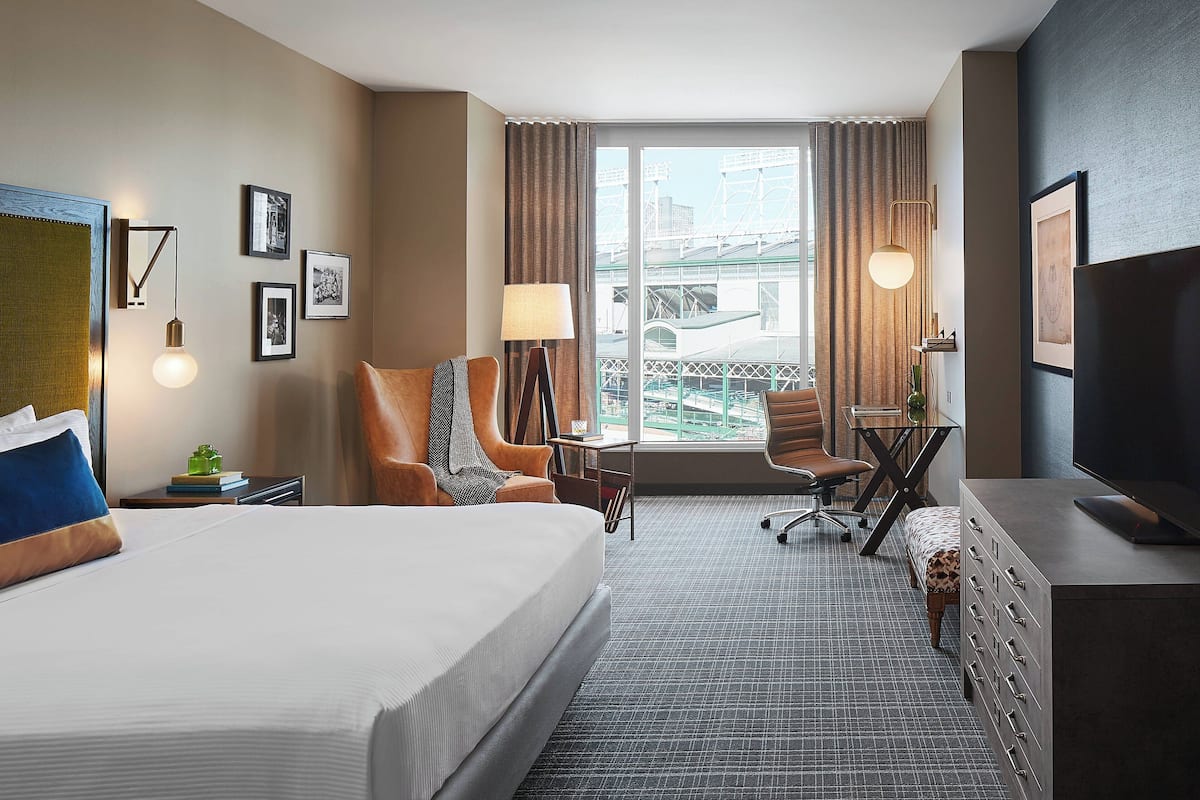 Habitación de hotel con una cama grande, un escritorio con silla, televisión y vistas a un puente por la ventana.