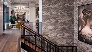 Ein modernes Interieur mit einer Ziegelwand, einer Treppe und einem großen gerahmten Kunstwerk.