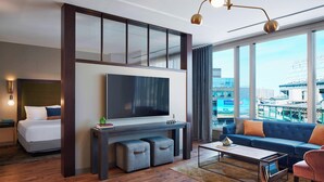 A modern hotel room with a large bed, a flat-screen TV, a sofa, and a city view. - Hotel Zachary Chicago, a Tribute Portfolio Hotel (Chicago)