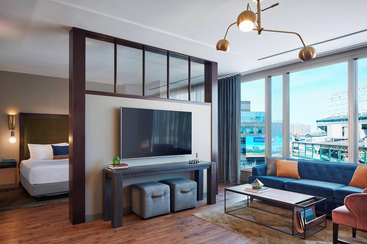 Una habitación de hotel moderna con una cama grande, un televisor de pantalla plana, un sofá y vista a la ciudad.