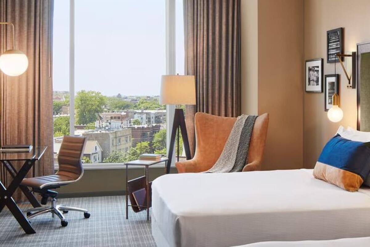 Habitación de hotel con una cama grande, un escritorio, una silla y vistas a la ciudad.