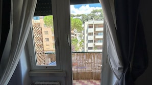 A room with a view of a balcony, a radiator, and a red chair. - Domum Vaticani (Rome)
