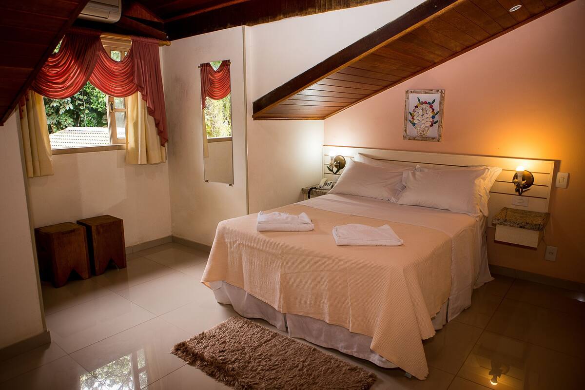 Un dormitorio con cama, mesitas de noche, una alfombra y un cuadro en la pared.
