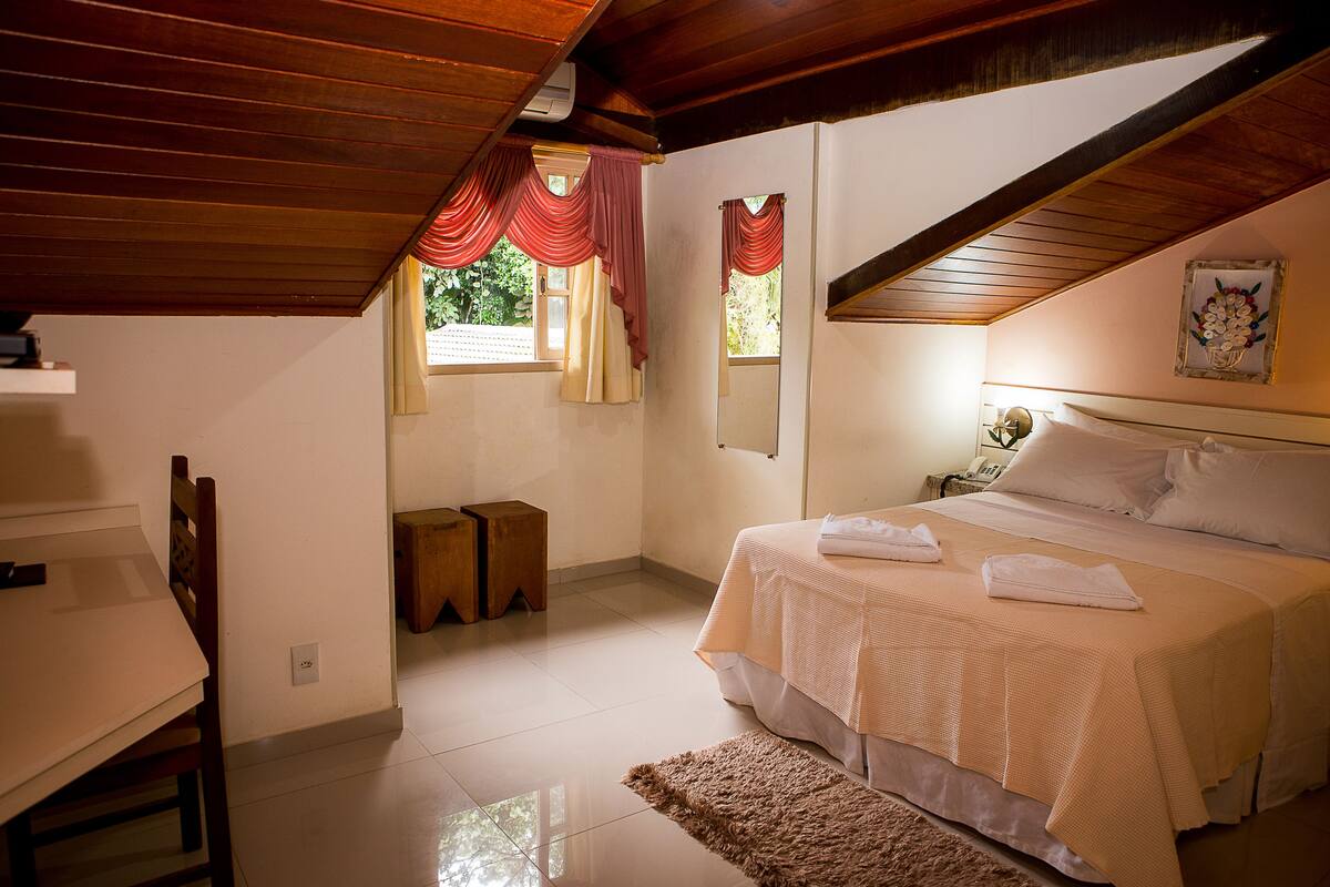 Un dormitorio con cama, escritorio y ventana con cortinas.