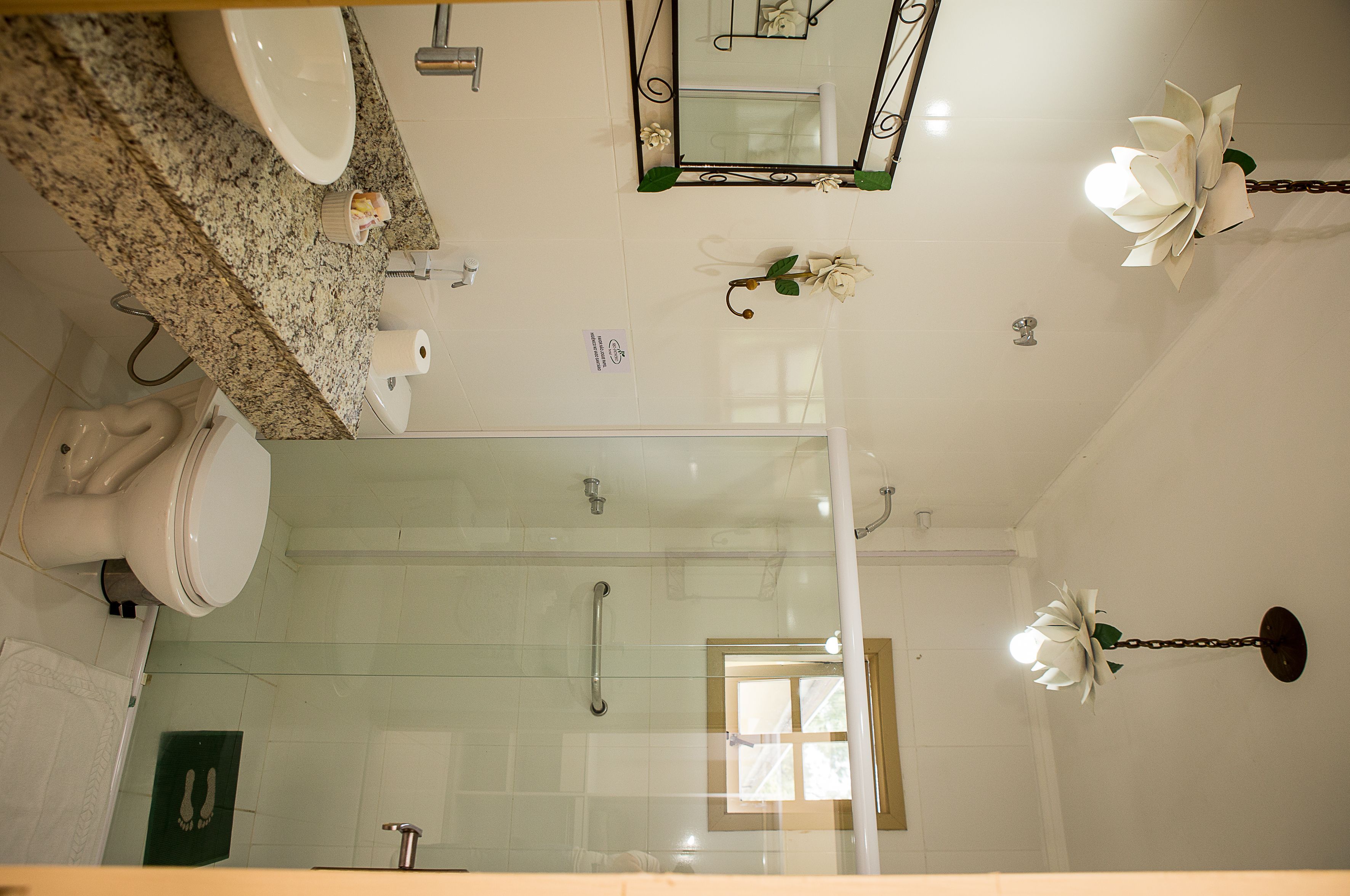 A bathroom with a toilet, sink, shower, and a mirror.