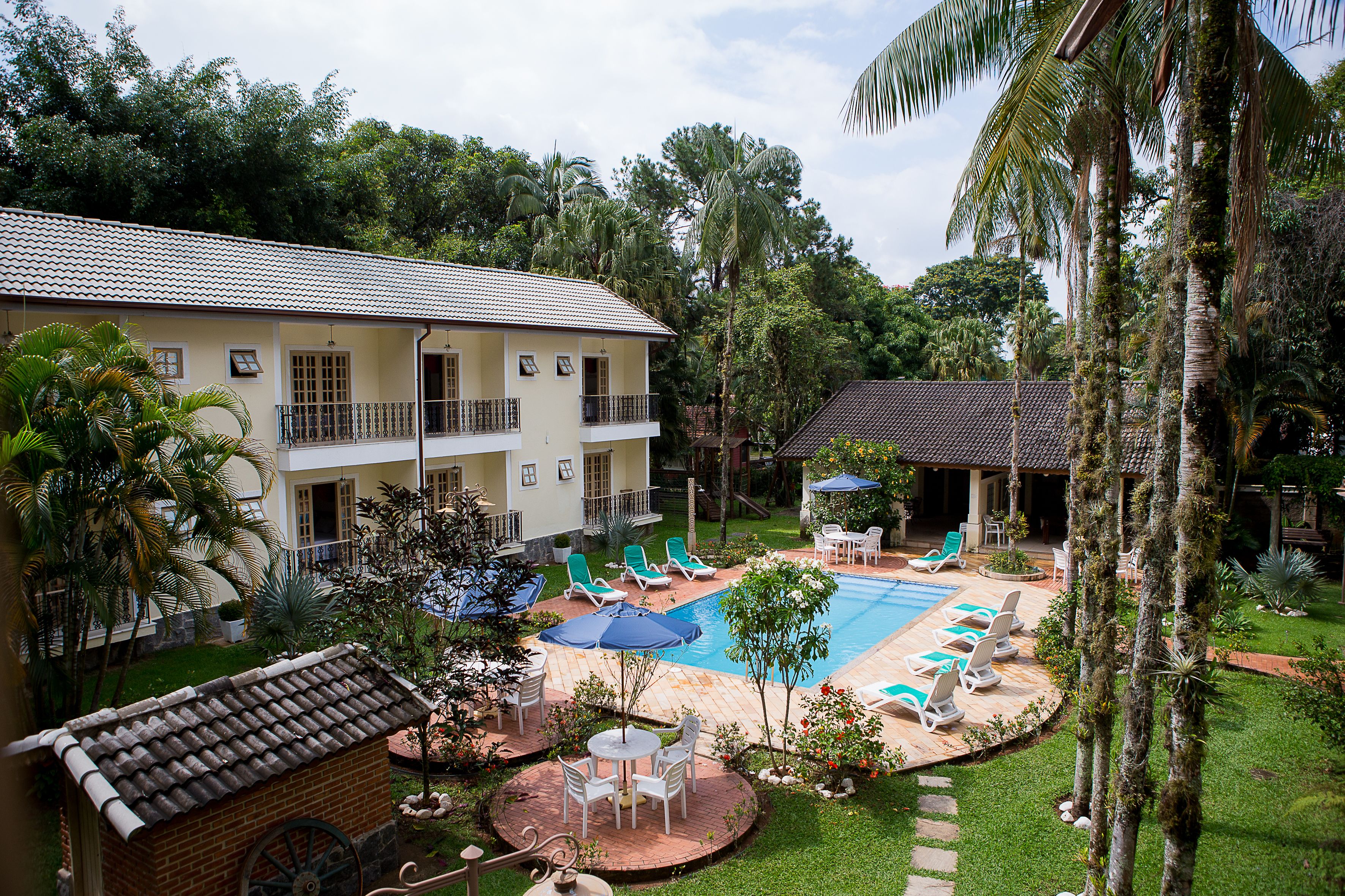 A hotel with a swimming pool, lounge chairs, and a garden area.