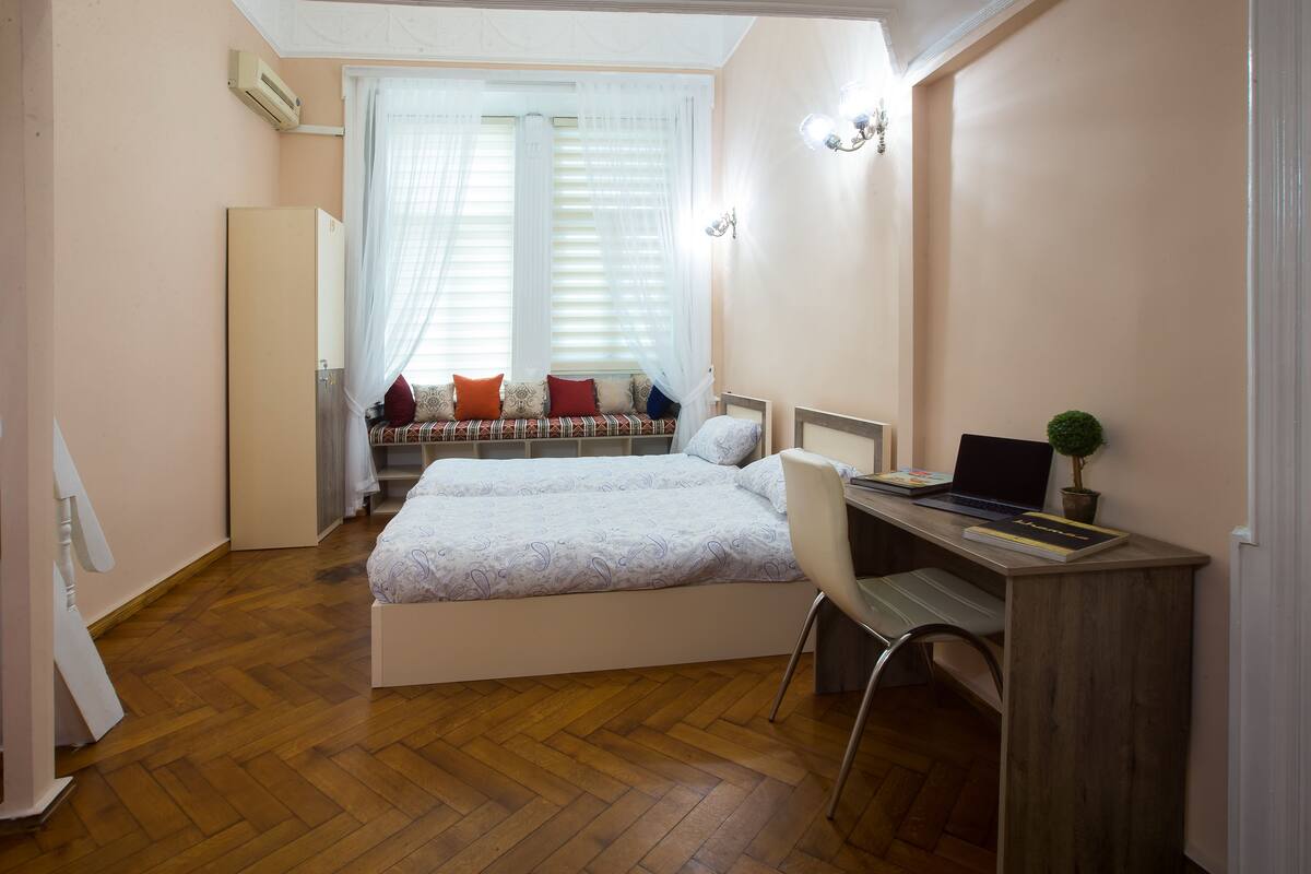 A bedroom with a bed, a desk, and a chair.