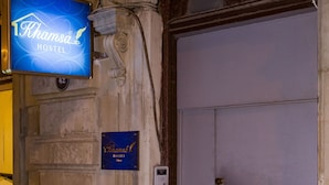 Un bâtiment avec une porte fermée et une enseigne indiquant « Khamsa Hostel » au-dessus.