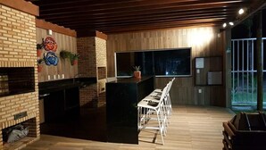 Una cocina moderna con una isla negra, sillas blancas y una pared de ladrillo.