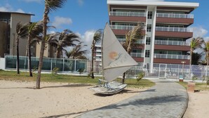 Un paseo marítimo que lleva a un edificio con una escultura de velero.
