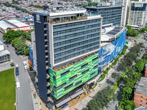 A multi-story building with a modern design, featuring a rooftop terrace and a large advertisement on the side.
