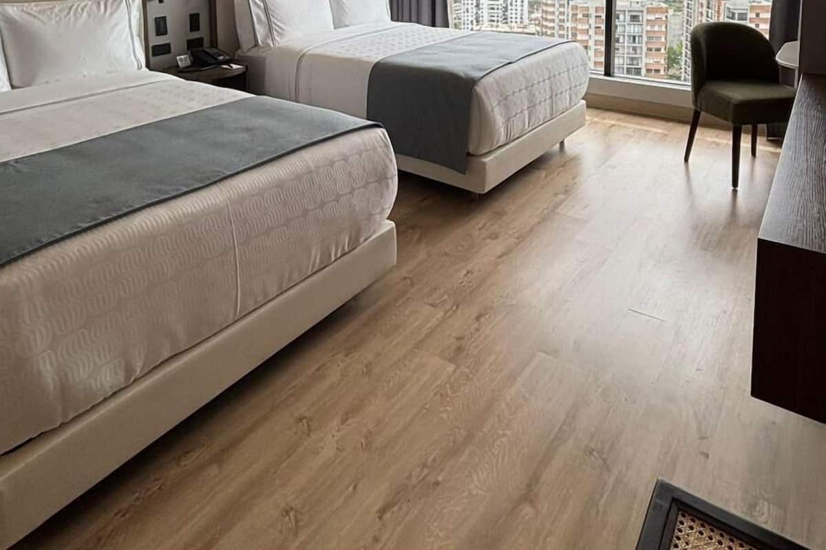 Een hotelkamer met twee bedden, een groot raam met uitzicht over de stad, een kleine tafel en een stoel.