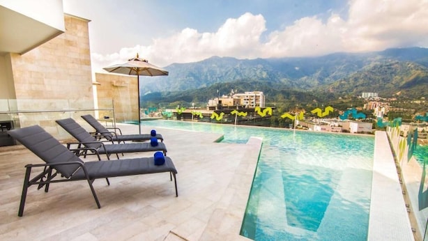 Una piscina en la azotea con sillones de descanso y vistas a la montaña.