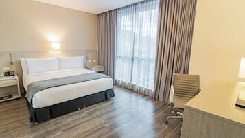 Una habitación de hotel con cama, mesitas de noche, escritorio y silla.