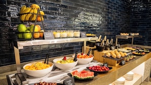 Un bufé con diversos alimentos, como frutas, ensaladas y sándwiches.