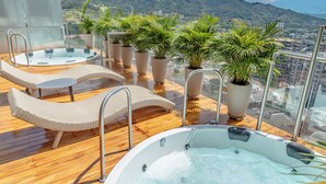 Terraza en la azotea con jacuzzi, sillones de descanso y plantas en macetas.